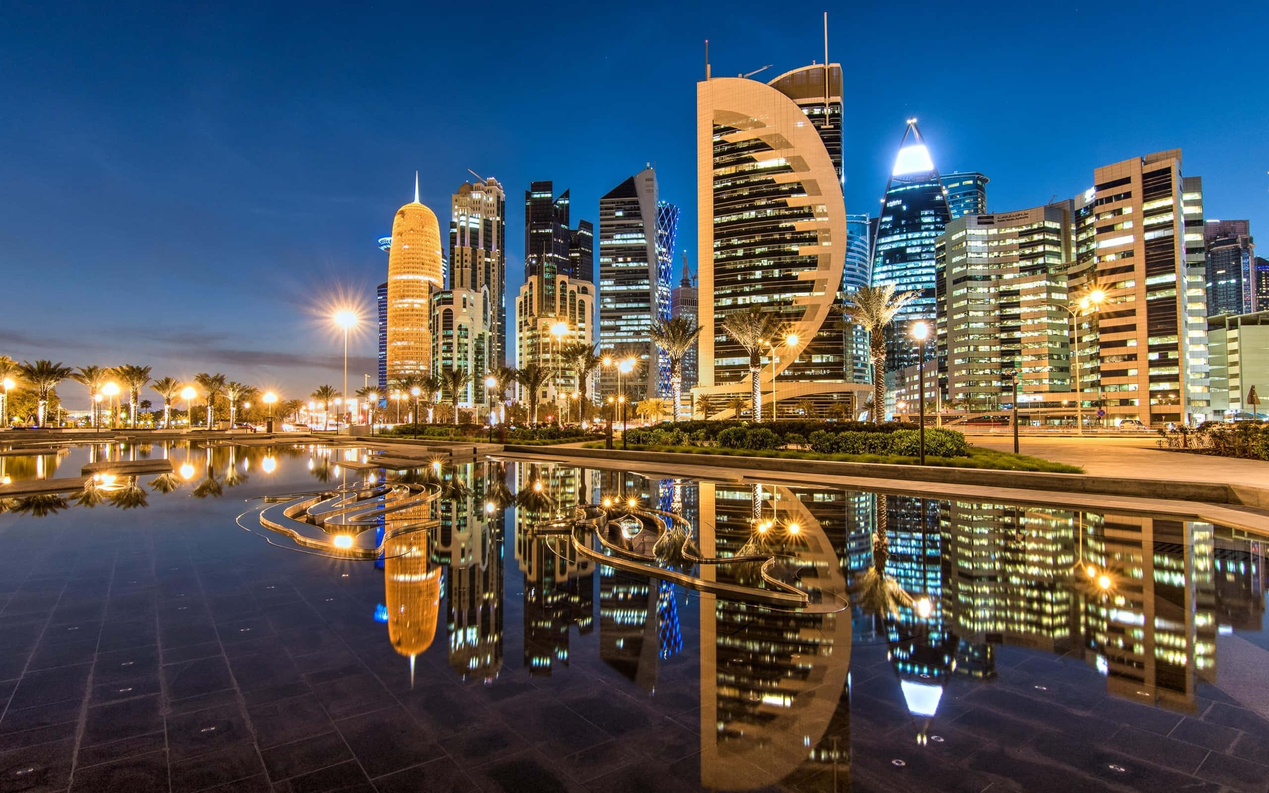 Qatar 桌布 壁紙 — 令人驚嘆的黃昏城市景觀，燈火通明的摩天大樓完美倒映在平靜的水面上。