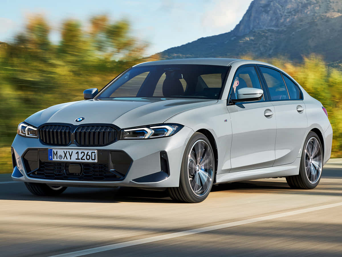 令人驚豔的BMW M850i xDrive敞篷車 壁紙 — 一架時尚的銀色BMW M3房車在陽光明媚的山路上飛馳，背景是模糊的綠植和岩石山峰。