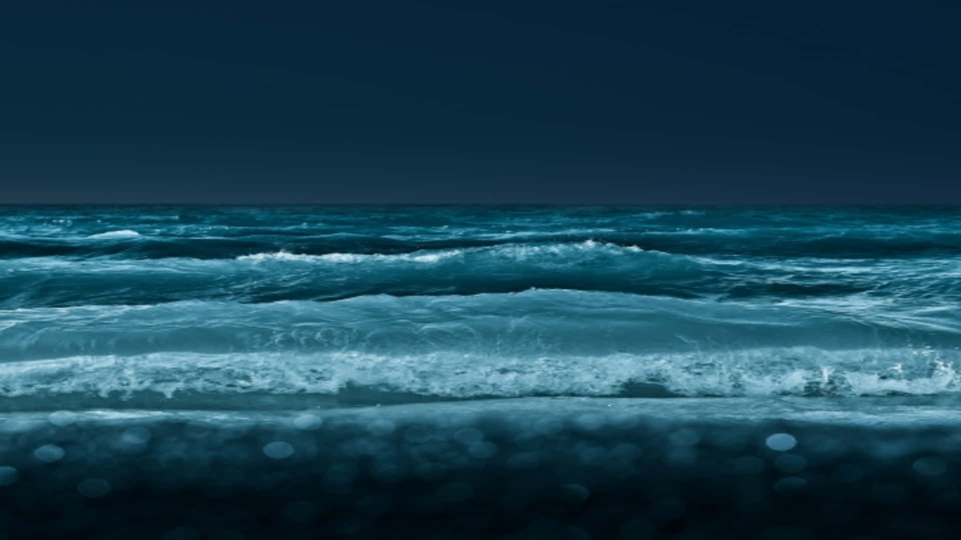 夜晚黑暗的海浪拍打沙灘。
