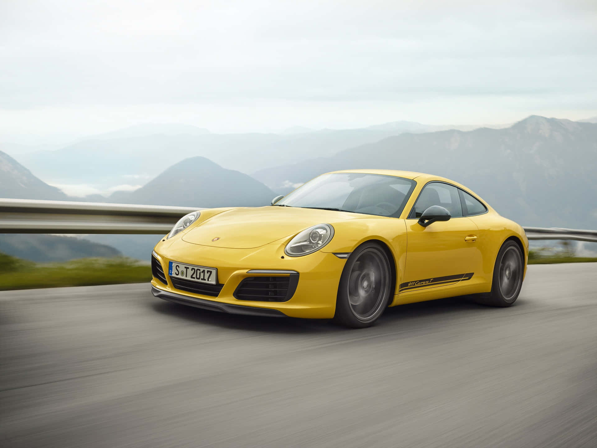 黃色保時捷911 Carrera T在山路上疾馳，呈現模糊動態。
