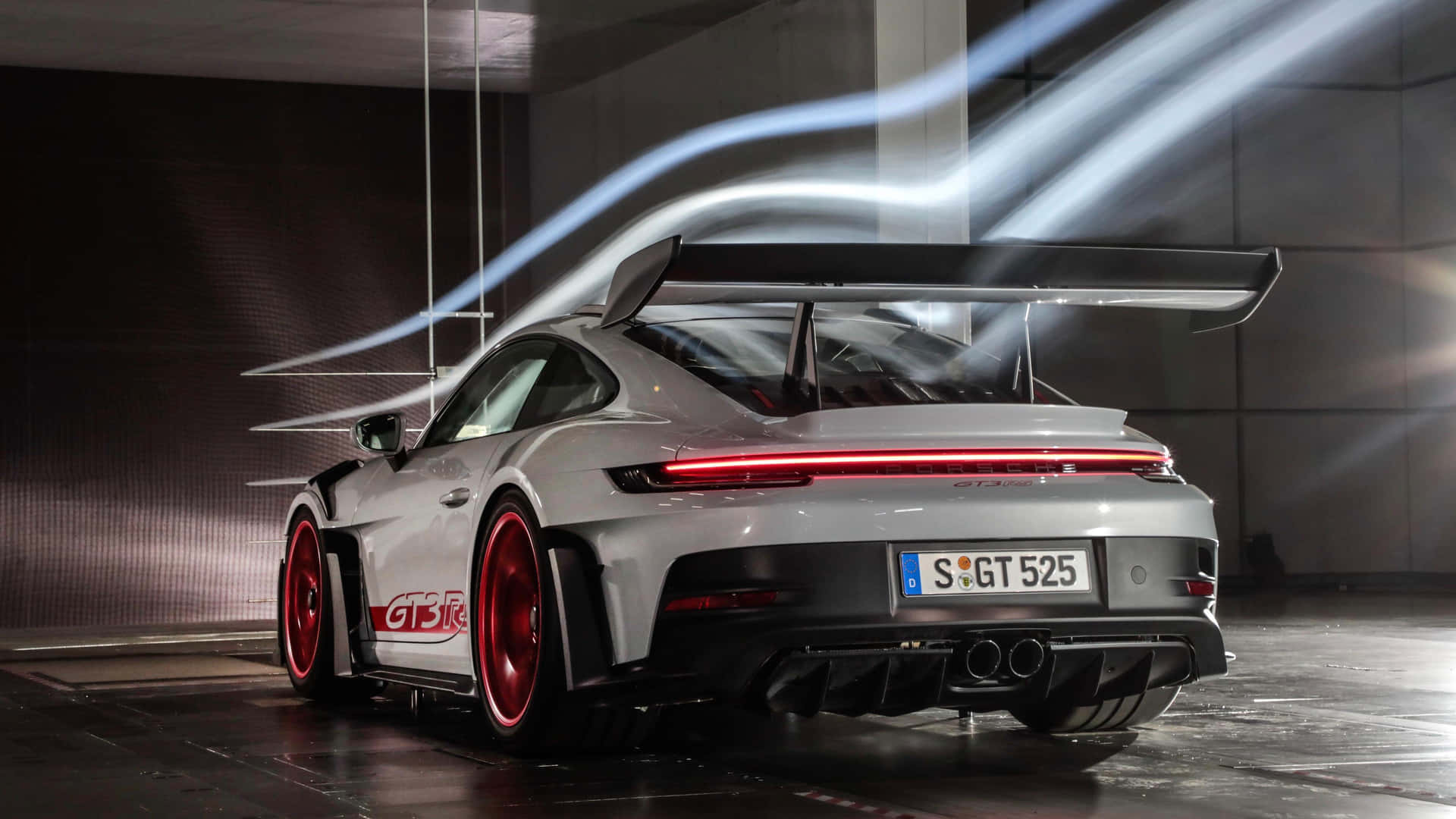 銀色保時捷911 GT3 RS，配備紅色輪圈和發光尾燈，在現代車庫中帶有光軌。