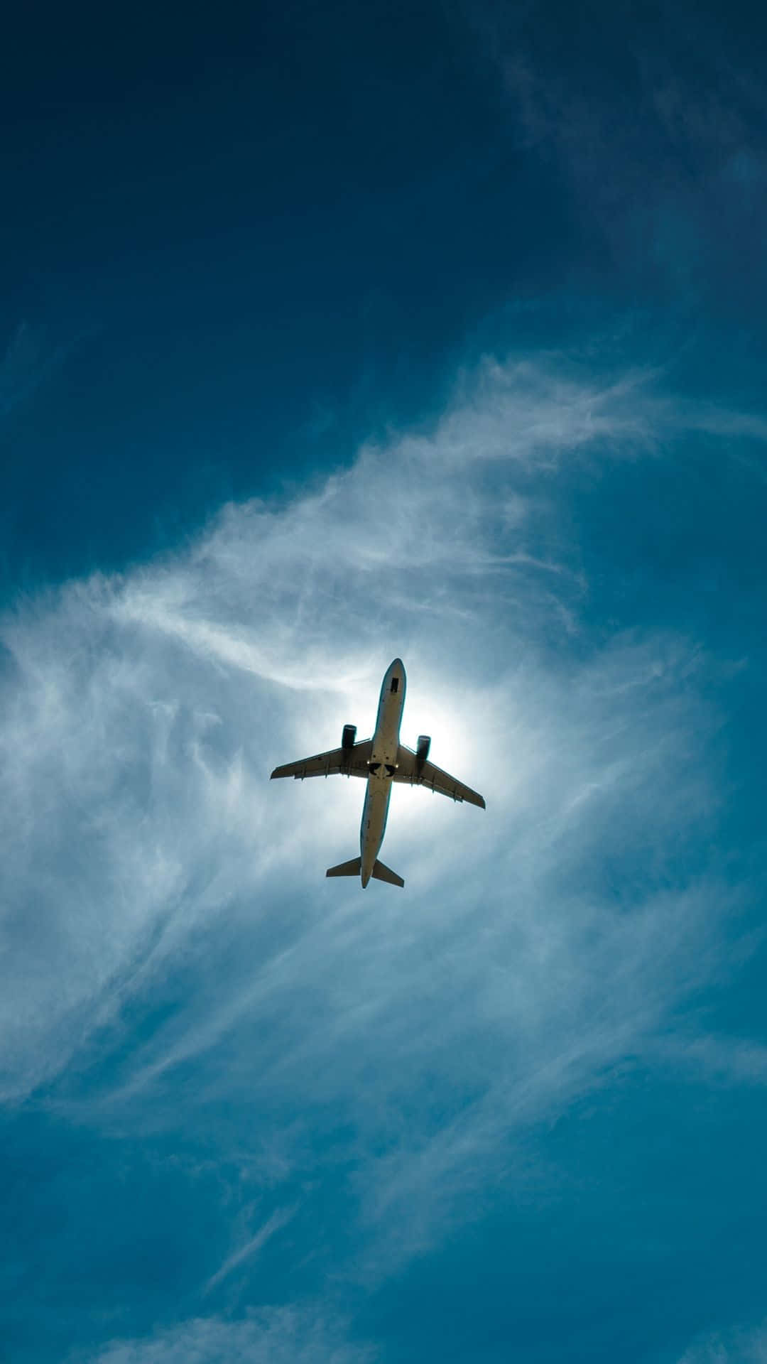 以 Android 小型飛機，時尚旅行 壁紙 — 一架商用飛機在湛藍的天空中翱翔，伴隨著縷縷白雲，在陽光的映襯下呈現出剪影。