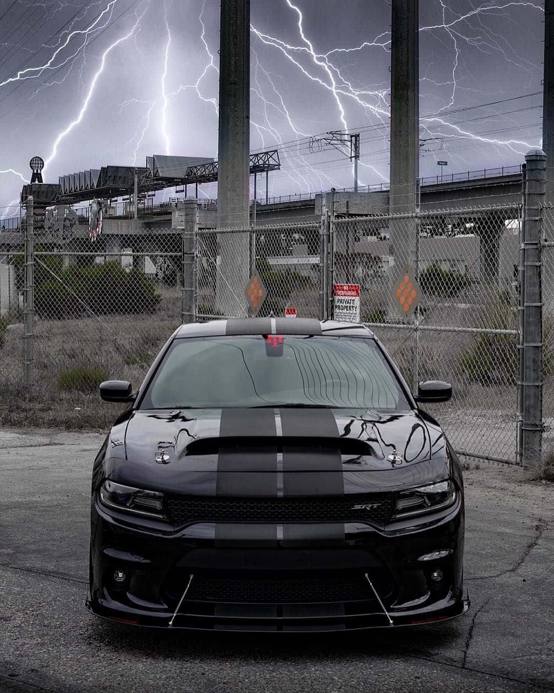 黑色肌肉車帶賽車條紋，在工業圍欄附近的閃電暴風雨下。