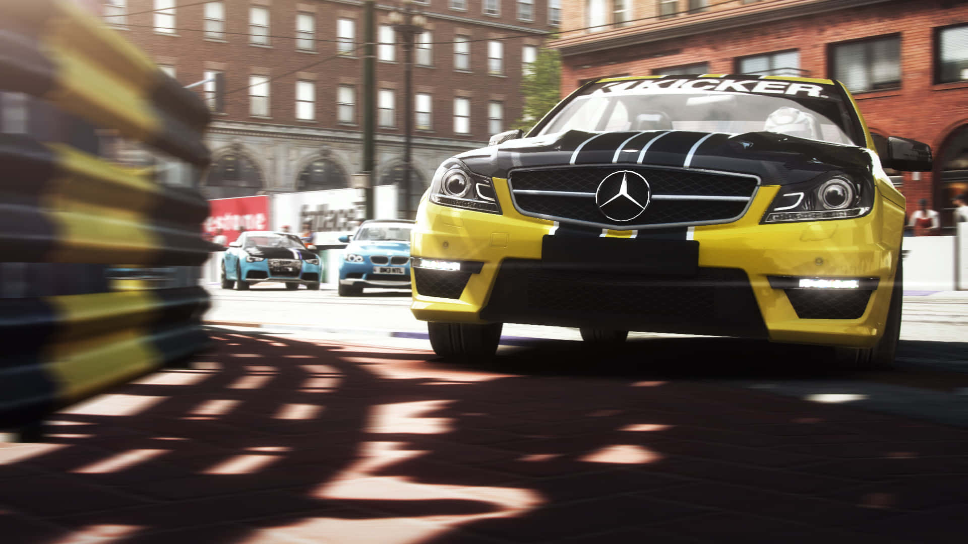 以 HD Grid Autosport 挑戰極限賽車！ 壁紙 — 一輛黃黑相間的梅賽德斯賽車在陽光明媚的磚砌街道上飛馳，經過的護欄和其他賽車手留下動態模糊效果。
