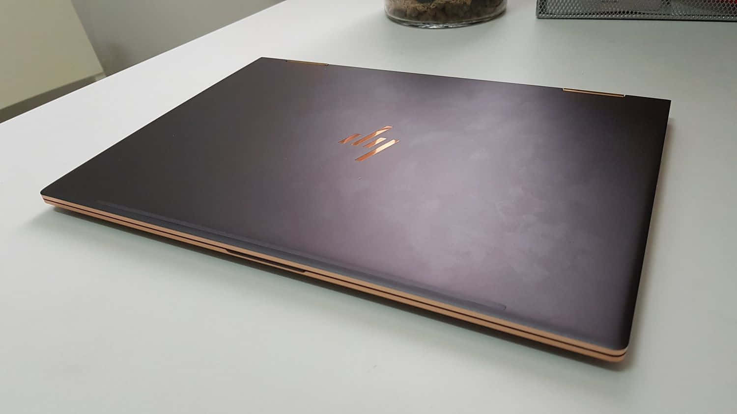 合上的手提電腦，紫色蓋子，玫瑰金色點綴，放在白色桌上。