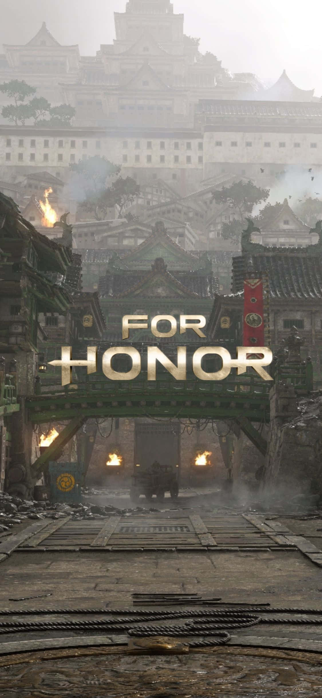 以 iPhone Xs For Honor 升級你的體驗 壁紙 — 一個被戰爭摧毀的日本城堡小鎮，燃燒的火把和一個金色的「FOR HONOR」標誌在霧濛濛的天空下。