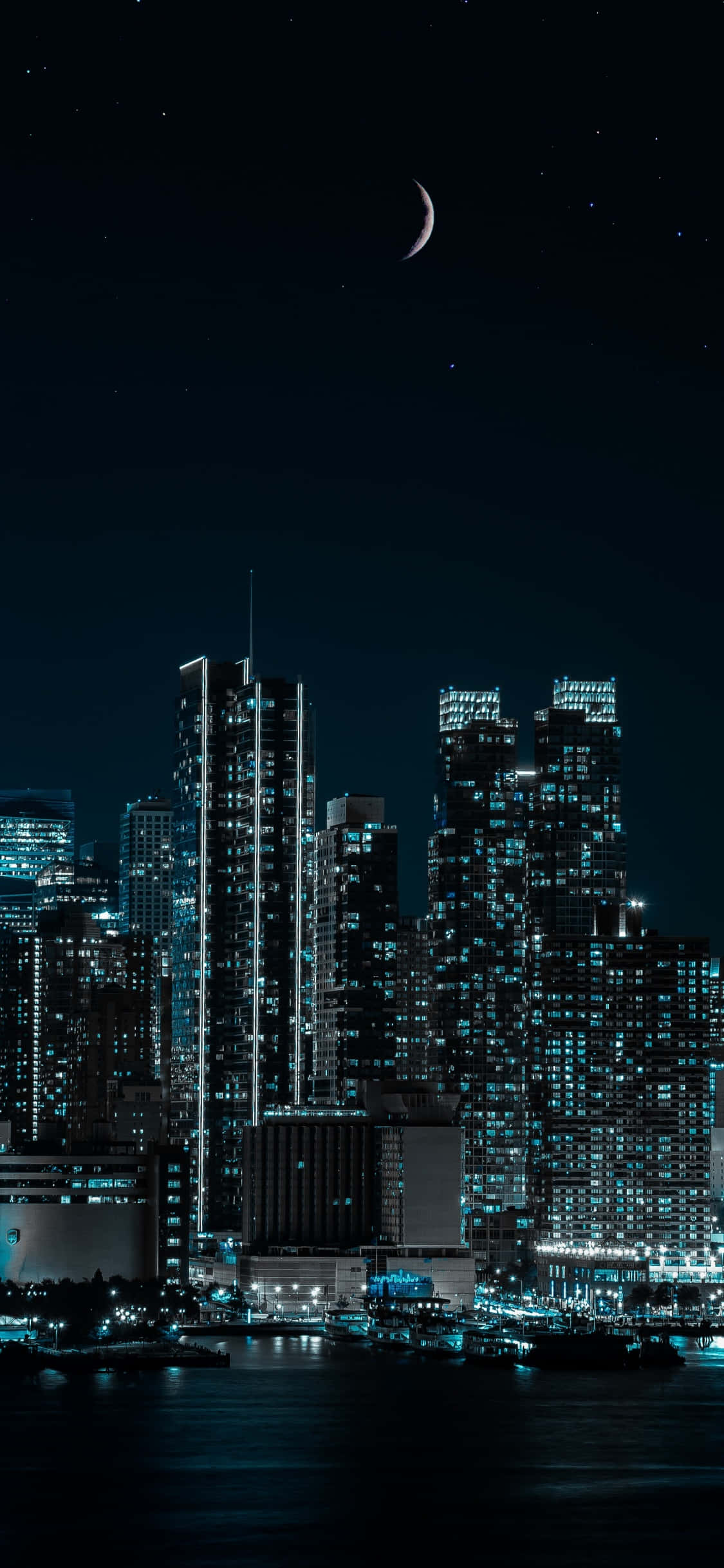以 iPhone XS 感受紐約的靈感，點燃你的想像力 壁紙 — 寧靜的夜景城市景觀，新月和星空下，發光的摩天大樓倒映在水中。