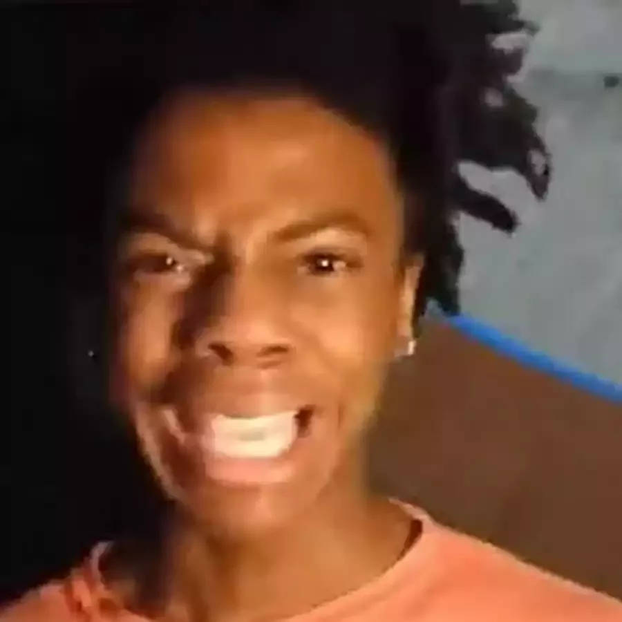 一個擁有捲髮嘅人穿著橙色襯衫，咧嘴而笑。