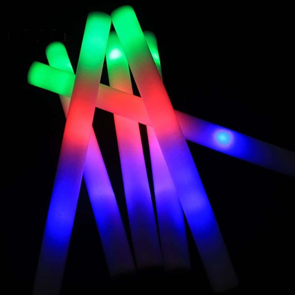 以「Light Up」點亮生活 壁紙 — 充滿活力的紅色、綠色和藍色發光棒在漆黑的背景下散發光芒，營造出節日的霓虹光輝。
