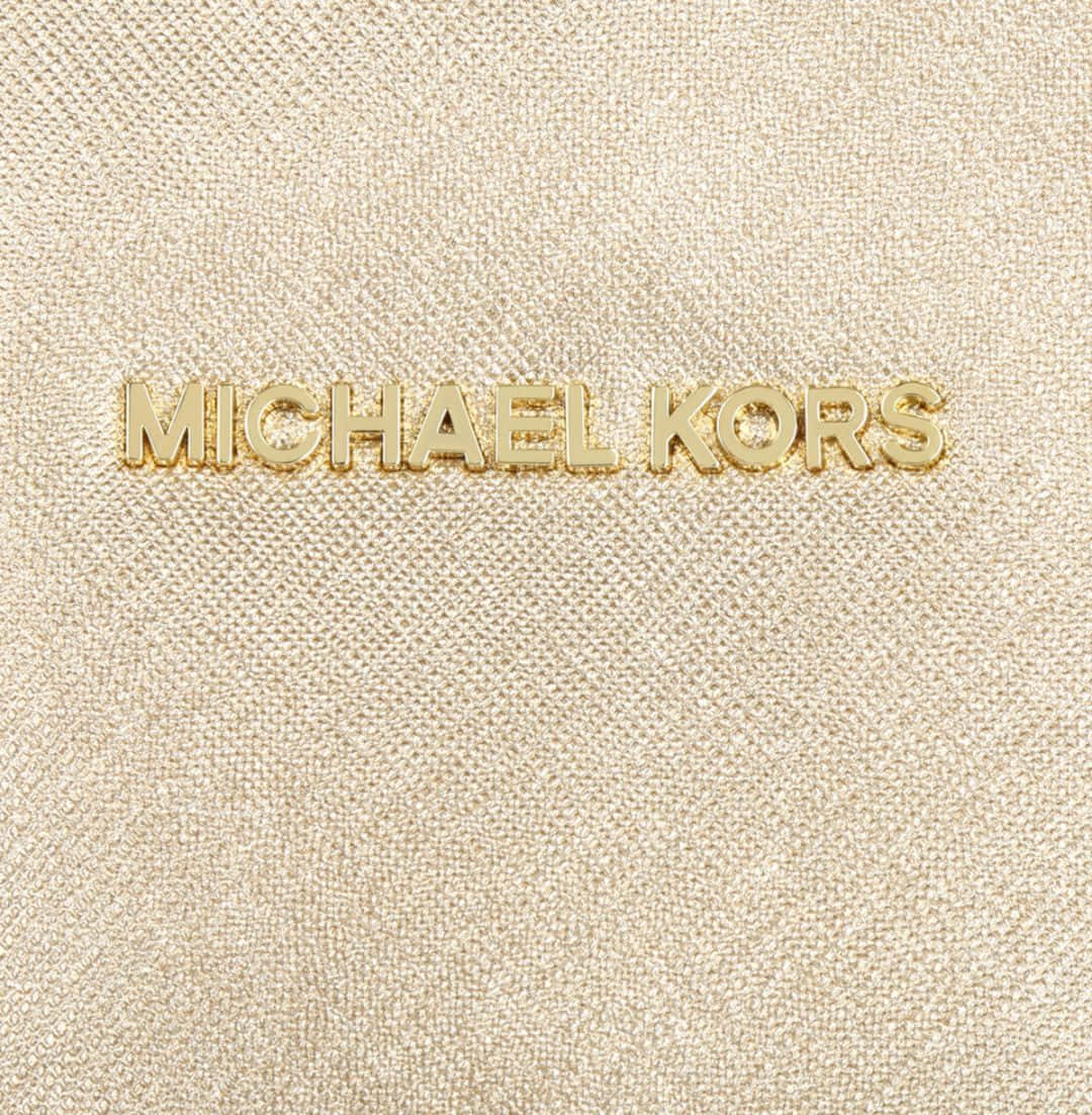 金色 Michael Kors 標誌在紋理米色布料上。