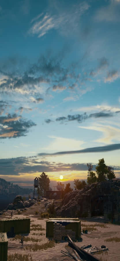 以 PUBG 率領戰場，盡在 iPhone X 壁紙 — 廣闊多雲的天空下，崎嶇的沙漠景觀上夕陽西下，散落著工業集裝箱和岩石地形。