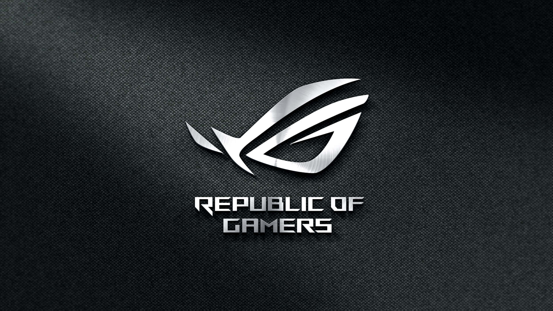 以 ROG 開啟你的真正潛能 壁紙 — 時尚的銀色 ROG 標誌在帶有微妙照明的紋理黑色布料背景上閃耀。