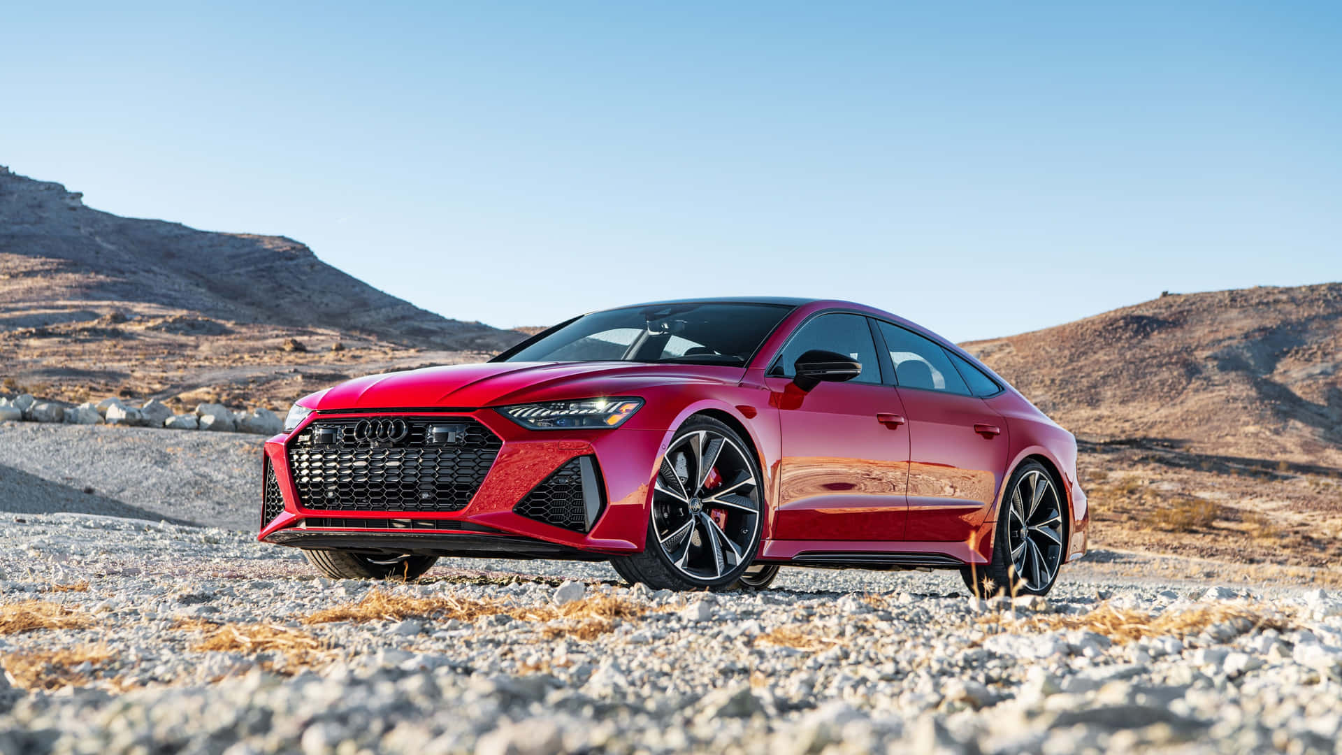 紅色奧迪RS7 Sportback在晴朗的藍天下停在岩石沙漠地形上。