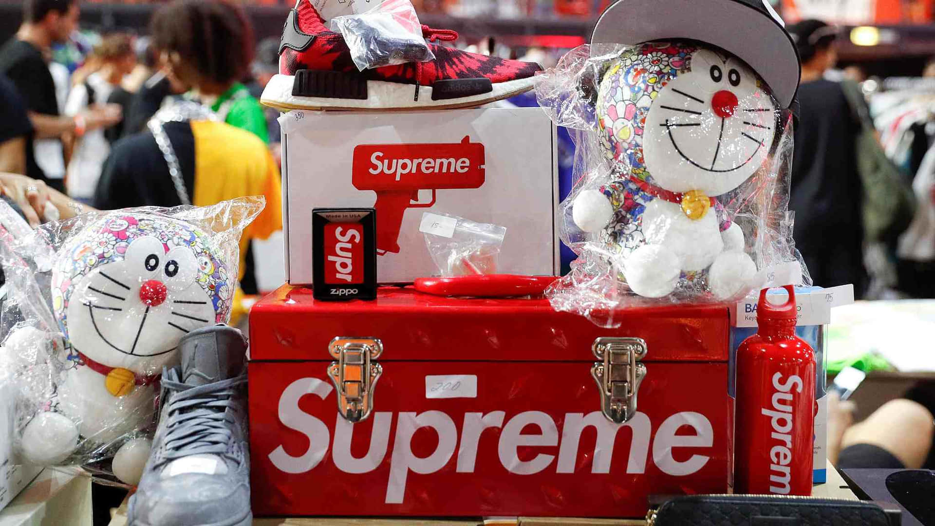 在繁忙的零售活動中，紅色Supreme行李箱內有多啦A夢毛公仔、運動鞋和Zippo打火機。