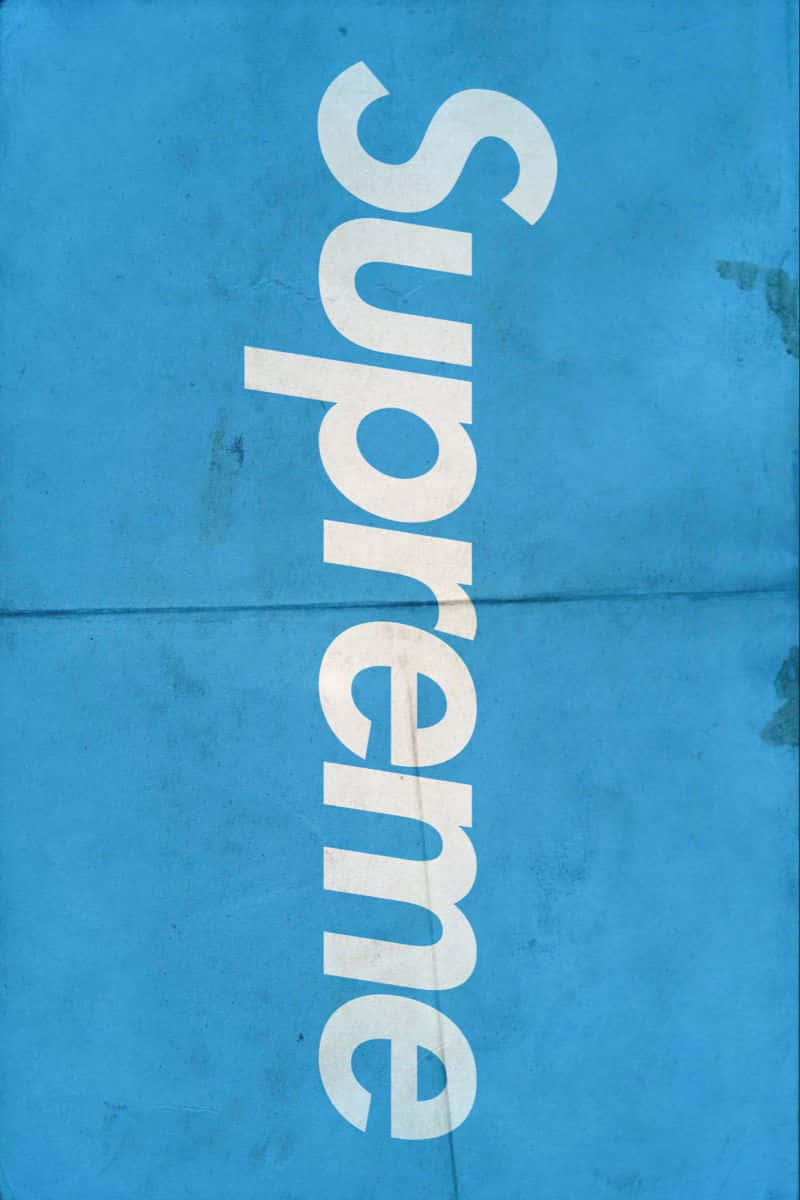 以 Supreme 藍色系列在街頭展現獨特風格 壁紙 — 大膽的白色 'Supreme' 標誌斜向橫跨帶有皺摺和污漬的紋理藍色背景。