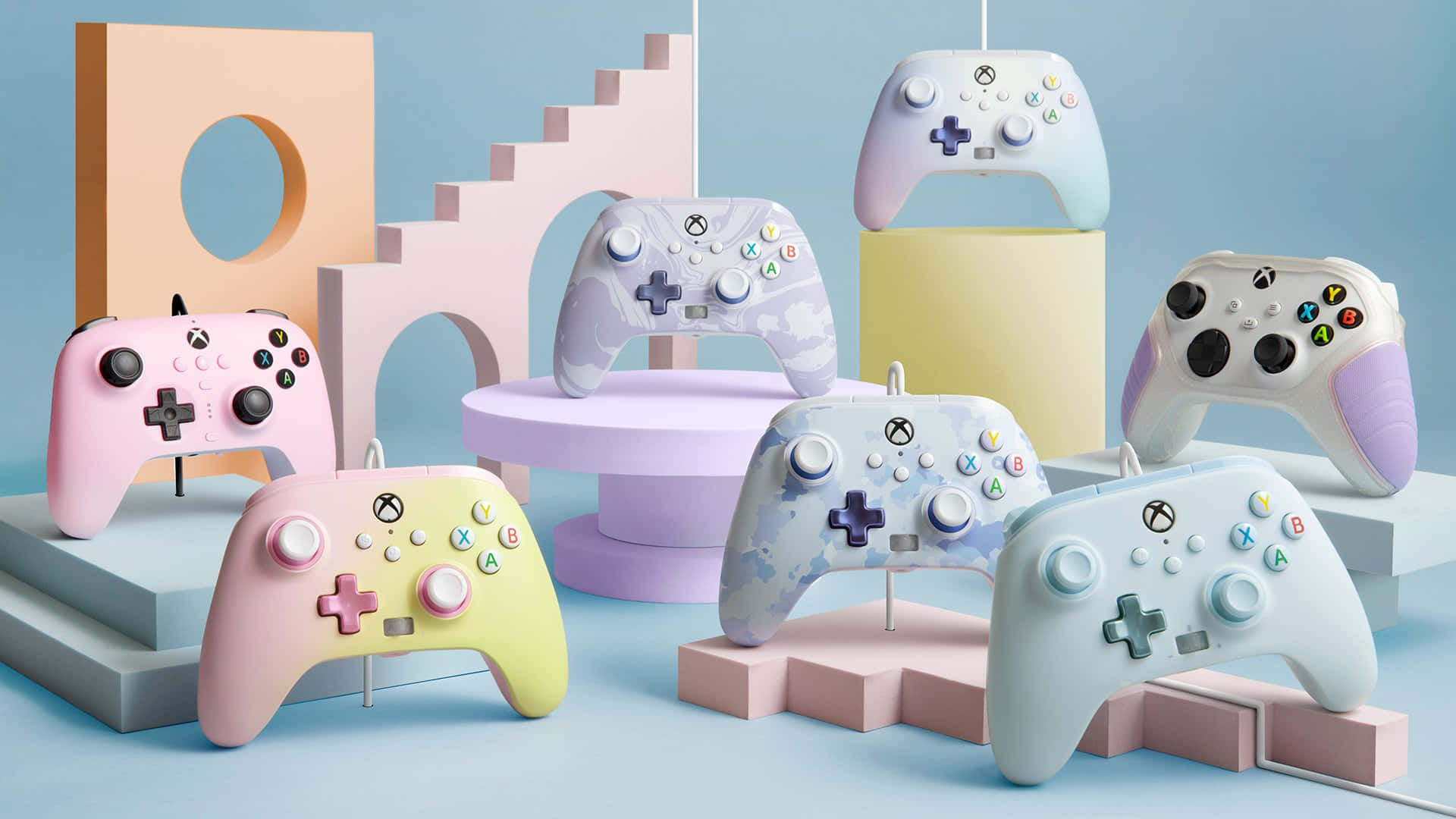 一系列粉彩色Xbox手掣排列在彩色幾何支架上。