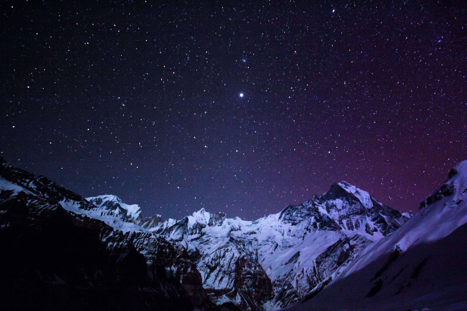 在星空紫色夜空下積雪的山脈與極光。