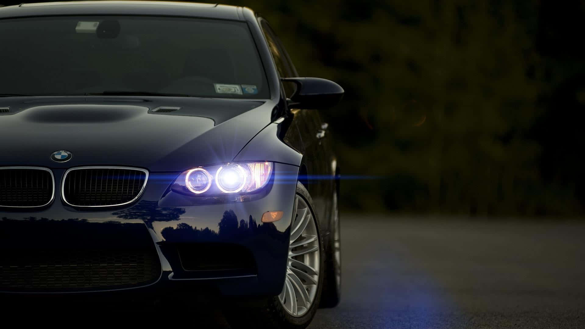 夜間道路上，深藍色BMW跑車亮著明亮的車頭燈。