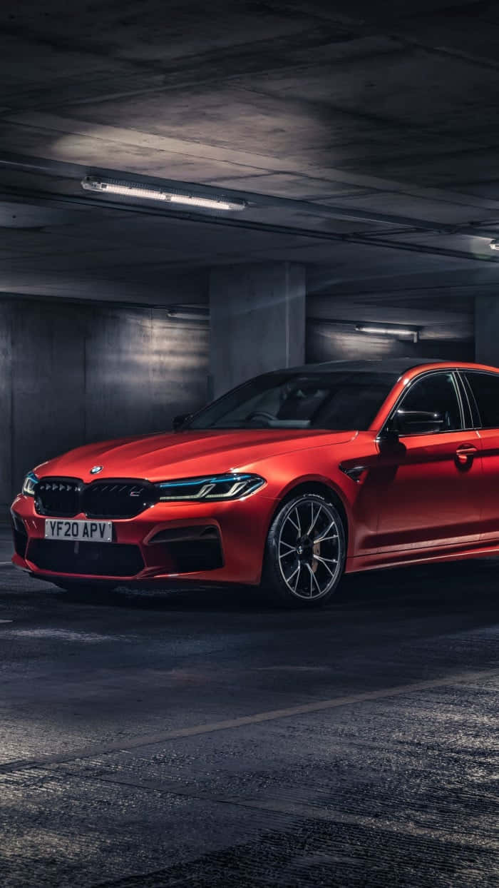 紅色BMW M5停放在光線昏暗的地下停車場，旁邊有混凝土柱。