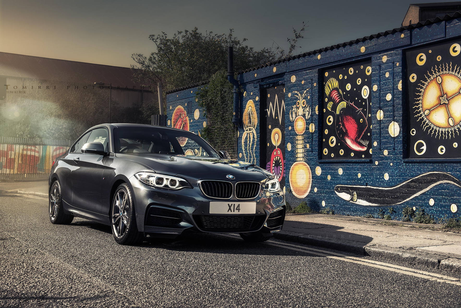 灰色BMW X14停泊在日落時分色彩繽紛的塗鴉牆旁。