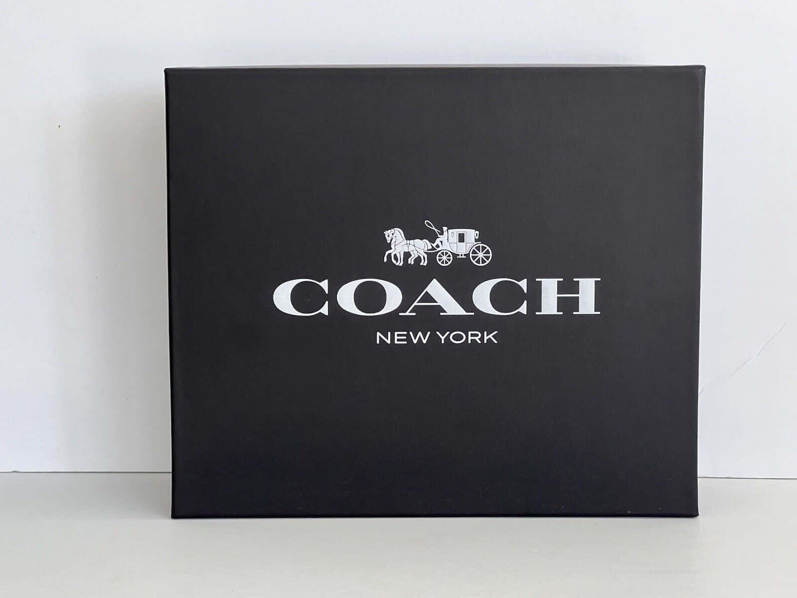 白色表面上的黑色 Coach New York 品牌盒子。