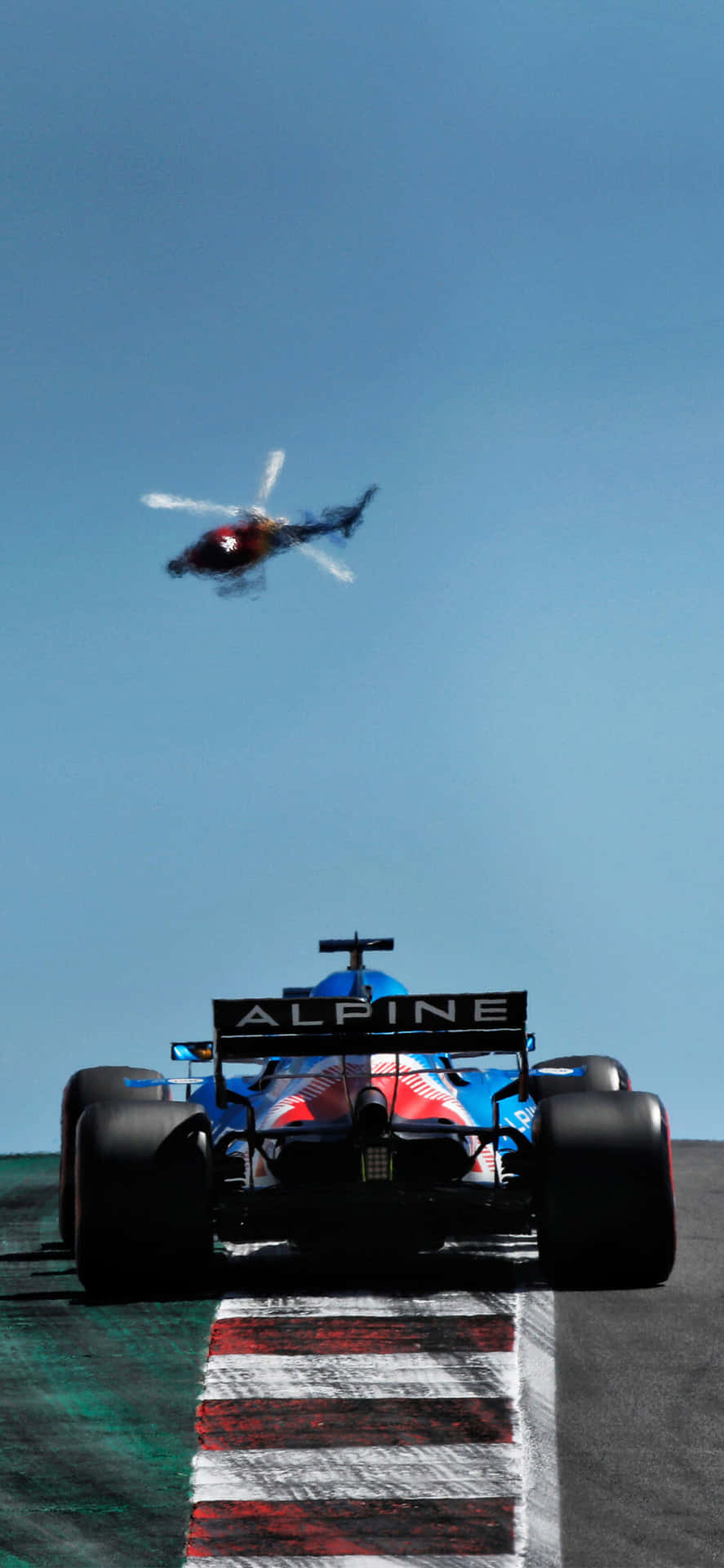 藍色Alpine F1賽車在賽道上奔馳，直升機在上空。