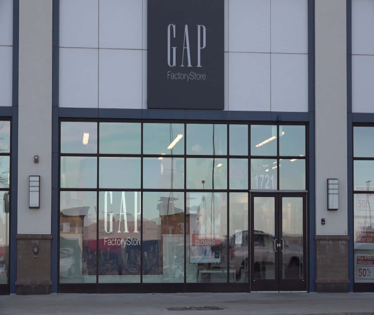 GAP Factory Store 正面，帶有關閉標誌和反射周圍環境的玻璃窗。