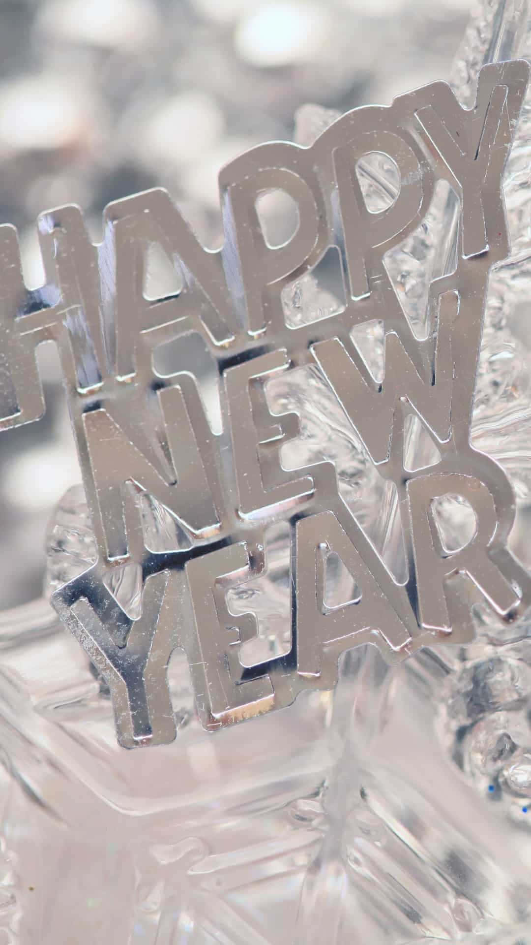 以iPhone 12迎接新一年 壁紙 — 閃亮的銀色 'HAPPY NEW YEAR' 字母放在閃爍的水晶裝飾上，背景柔和散景。