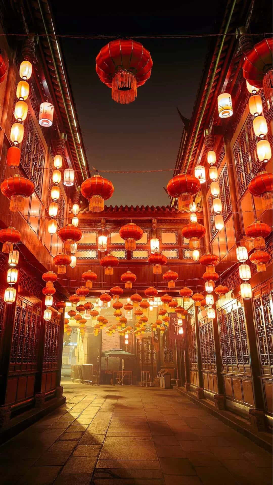 夜晚狹窄的小巷，由懸掛在傳統木建築之間的紅色和白色燈籠照亮。