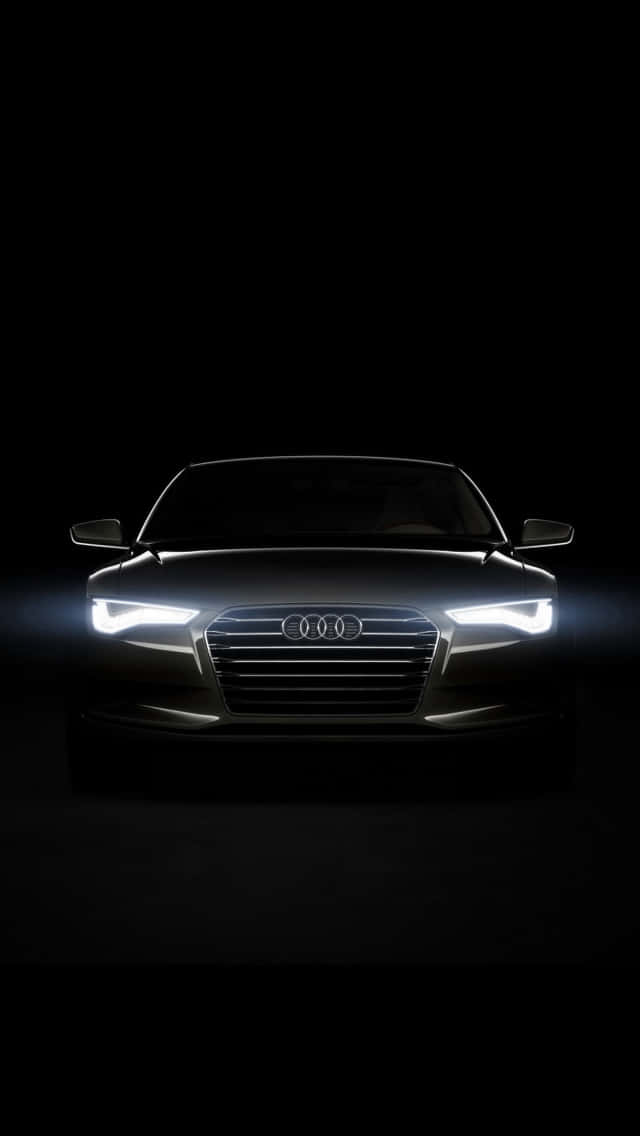 黑暗中閃耀著車頭燈的時尚銀色Audi汽車。