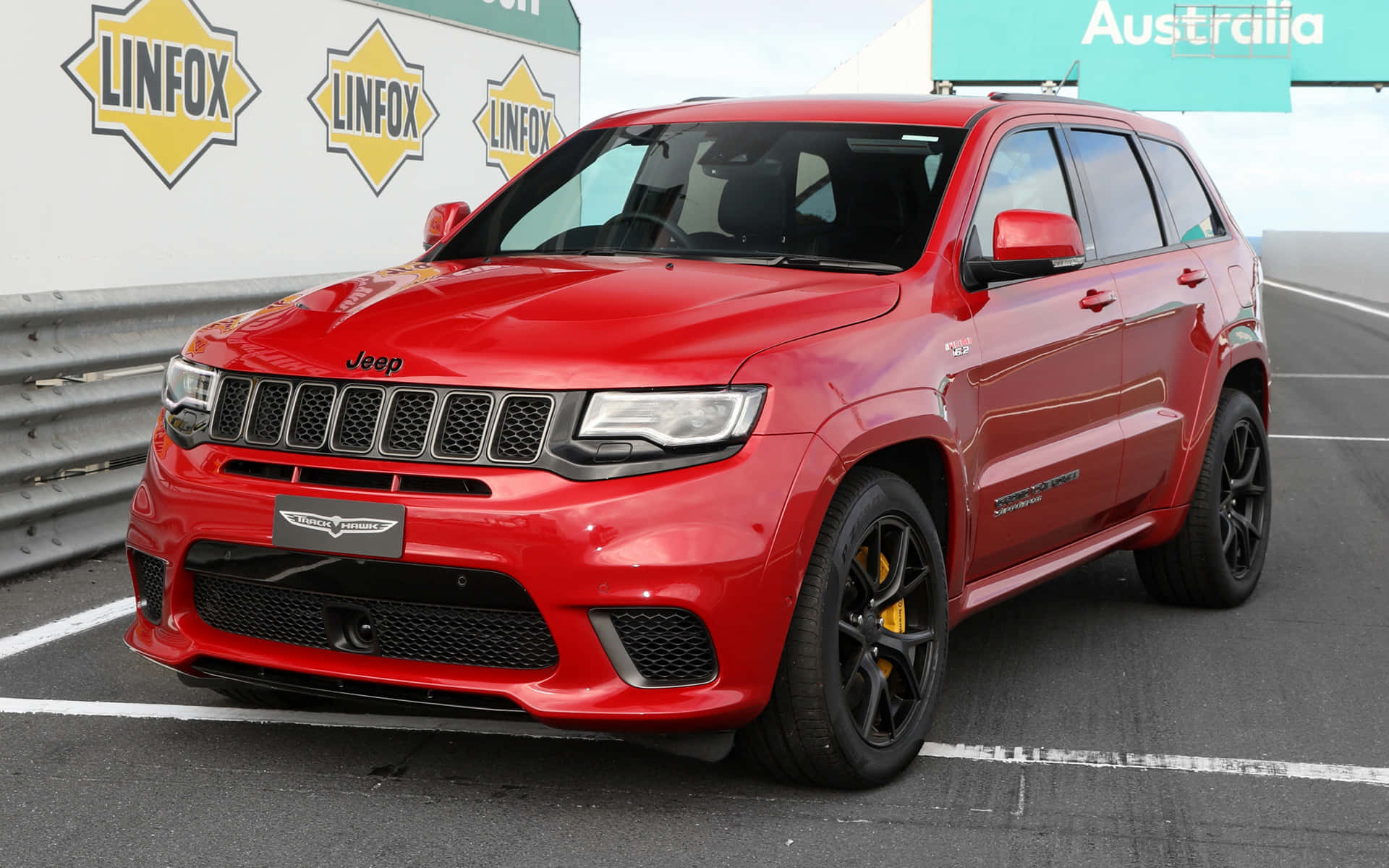 紅色Jeep Grand Cherokee Trackhawk停泊在瀝青上，靠近Linfox標誌。