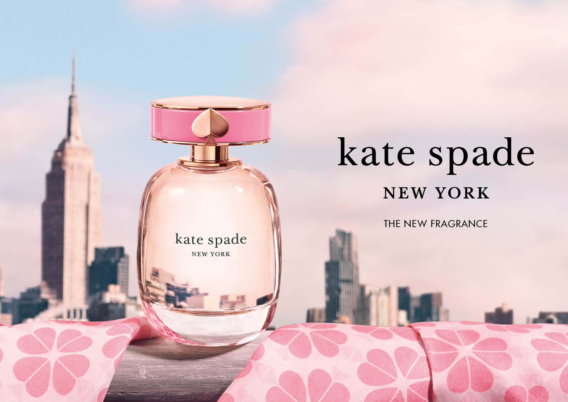 Kate Spade香水瓶放在花卉布料上，背景是紐約天際線。