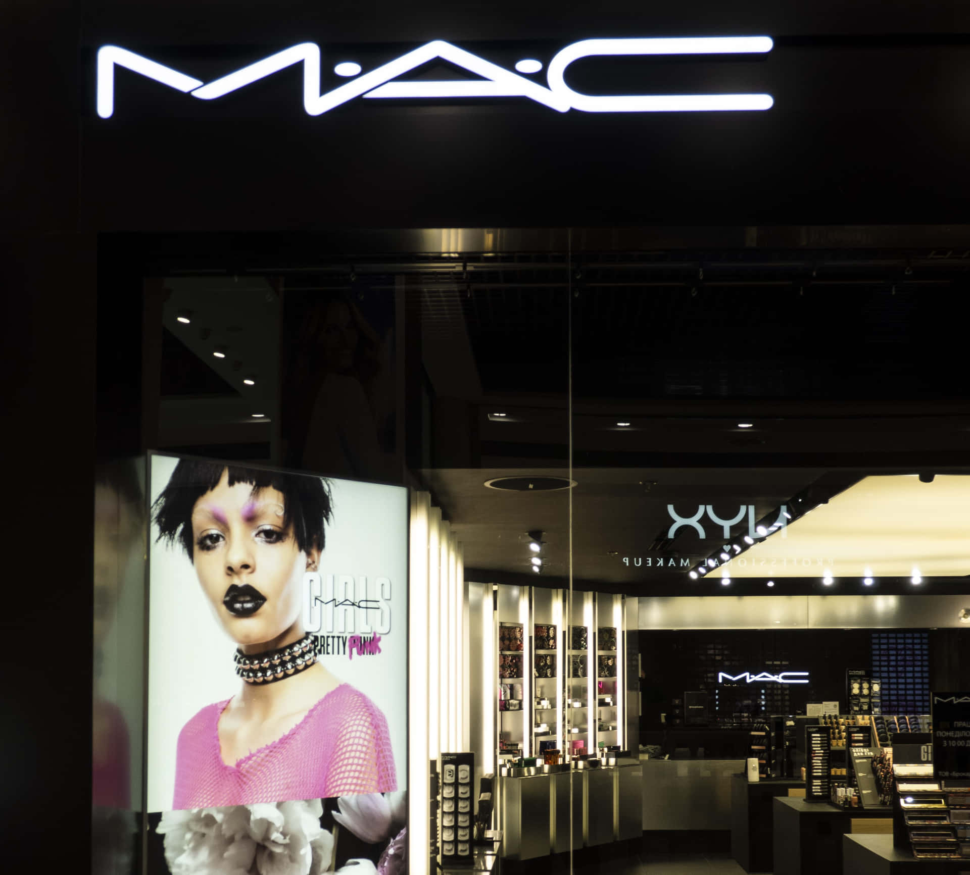 夜晚MAC化妝品店門面，有發光招牌和模特兒海報。