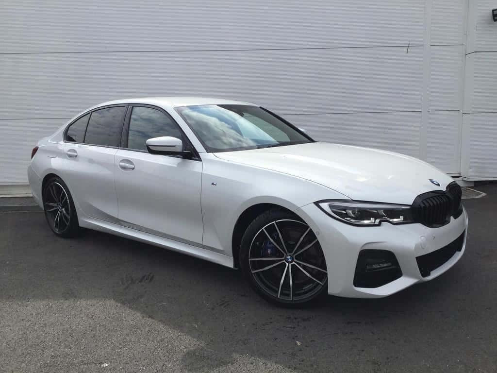 以M系列車款展現非凡魅力 壁紙 — 一輛時尚的白色BMW轎車配黑色輪圈，停在波紋金屬牆前。