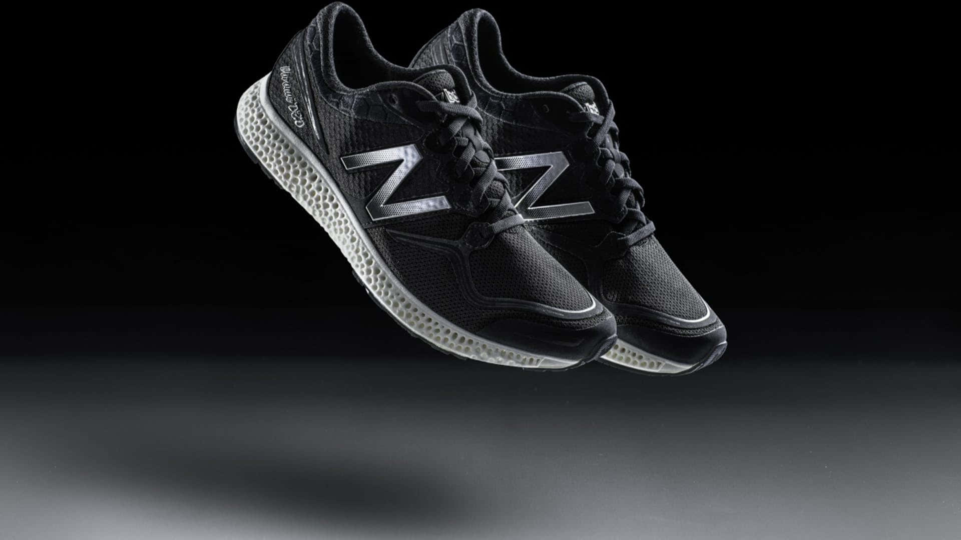 黑色New Balance運動鞋在昏暗的攝影棚中漂浮，光線柔和。