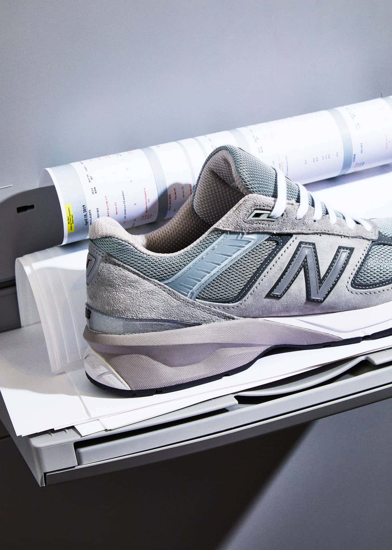 灰色 New Balance 運動鞋放在打印機托盤上，附近有打印好的文件。