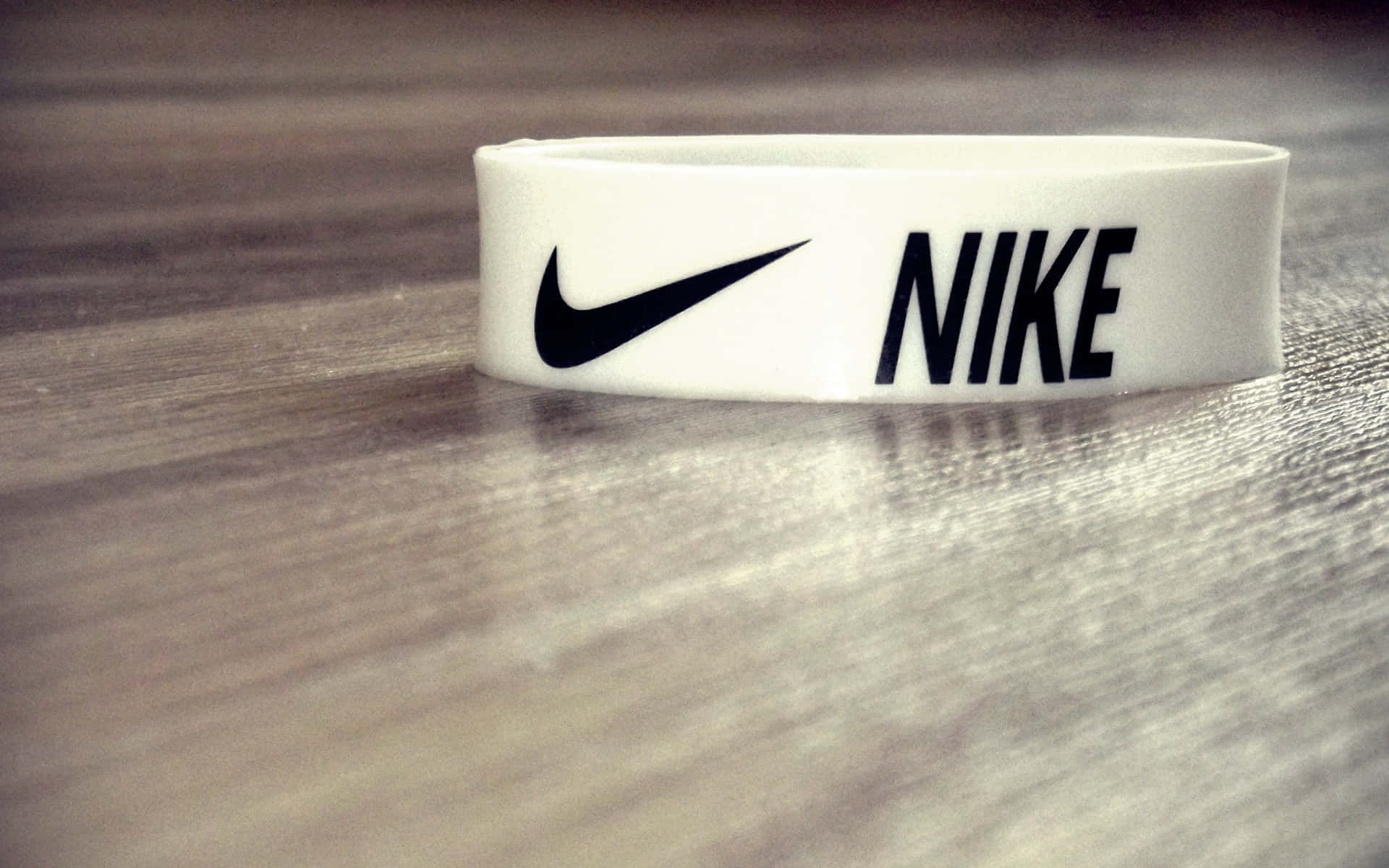 帶有黑色標誌的白色Nike腕帶，木質表面。