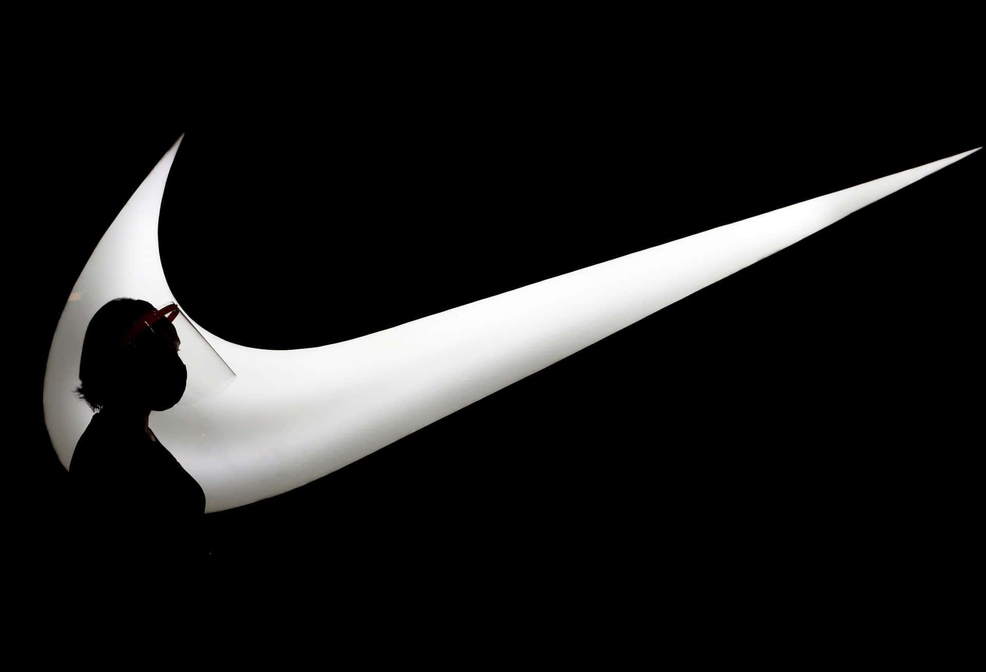 一個人在發光的Nike標誌前的剪影。