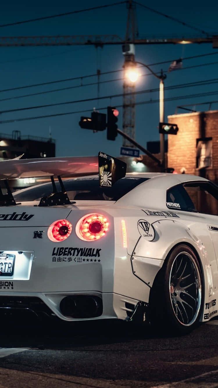 白色改裝日產GT-R，夜晚的城市街道十字路口。