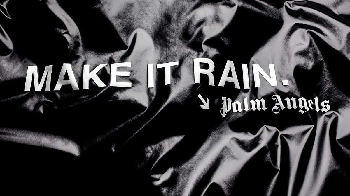 皺褶黑色緞面布料上的粗體白色文字寫著 make it rain palm angels。