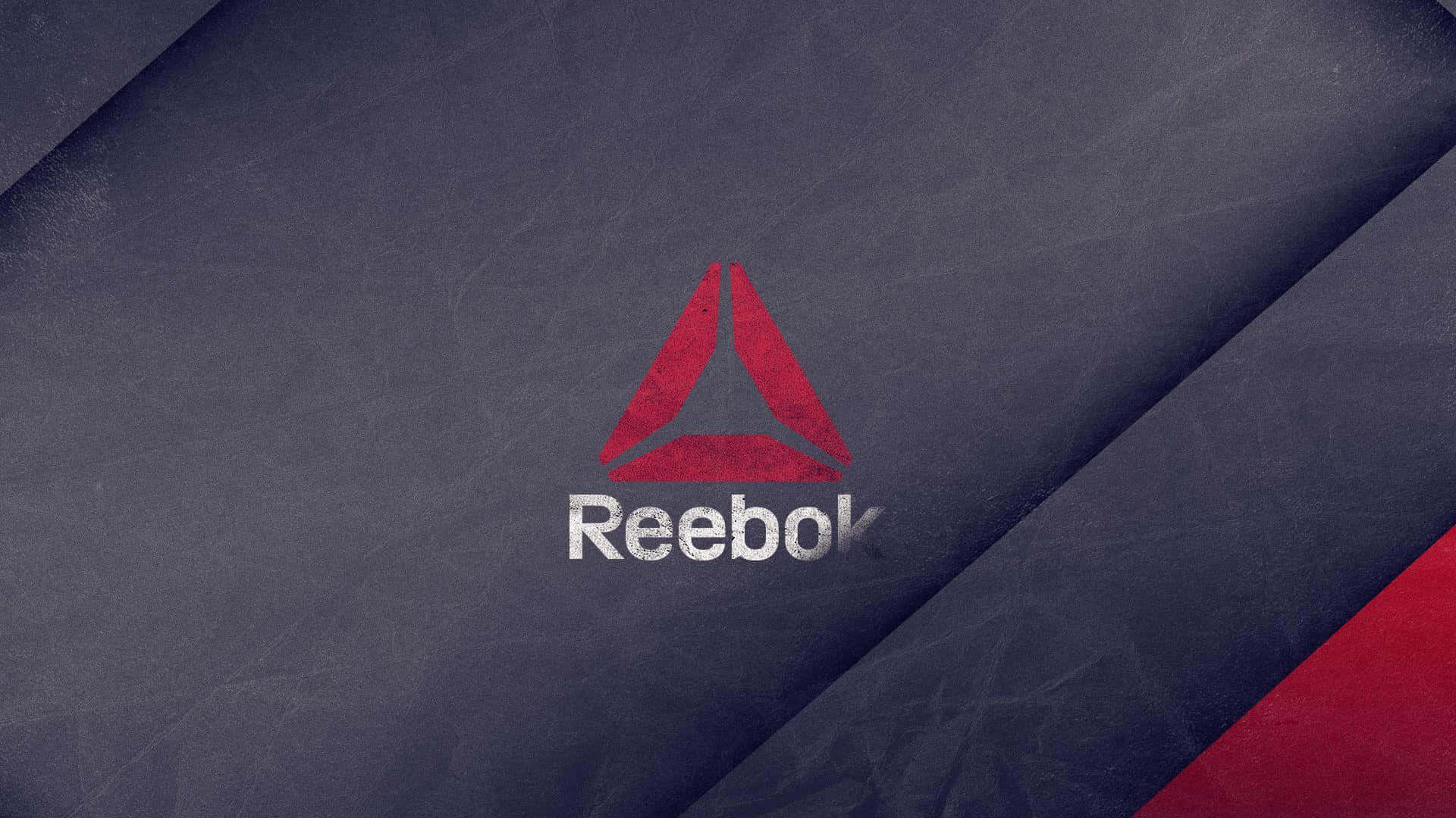 以Reebok提升你的表現力 壁紙 — 一個大膽的紅色 Reebok 標誌，白色文字居中，位於帶有紋理的深藍色布料背景上，並帶有紅色對角線裝飾。