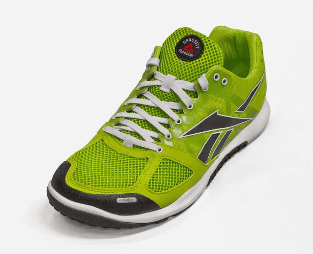 以Reebok提升您的訓練水準 壁紙 — 在工作室燈光下，一雙明亮的青檸綠色Reebok CrossFit運動鞋，配有白色鞋帶和黑色點綴。