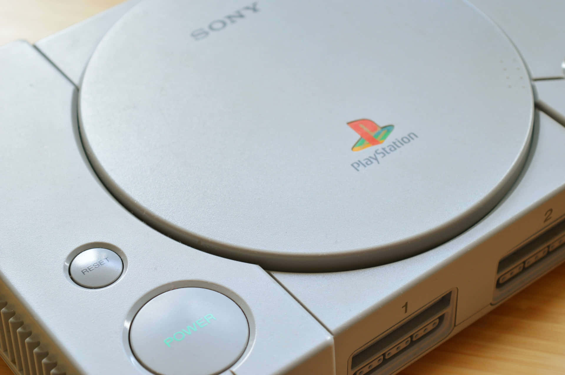 木頭上帶有發光電源按鈕的銀色PlayStation 1主機。