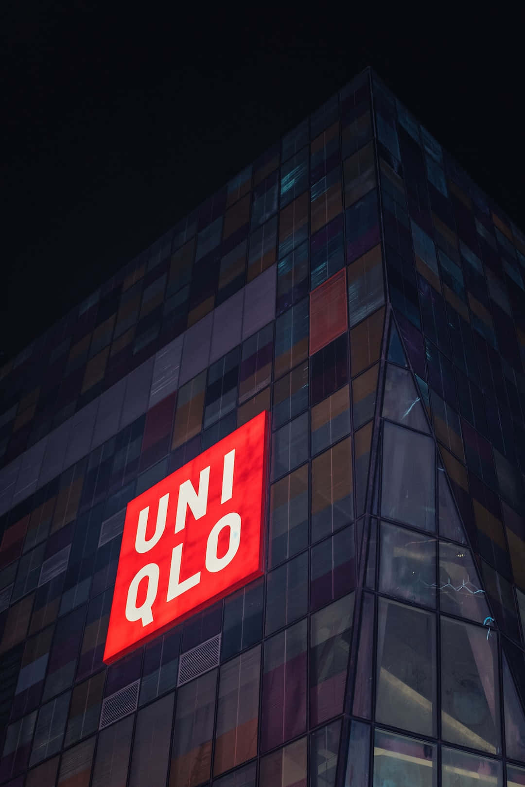 夜間玻璃建築上明亮照明的UNIQLO標誌。