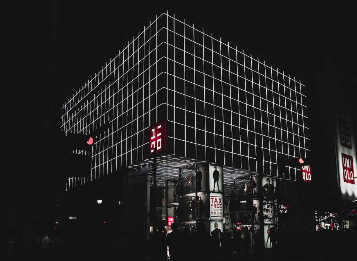 夜晚中一座現代建築，帶有發光的白色網格線和紅色Uniqlo標誌。