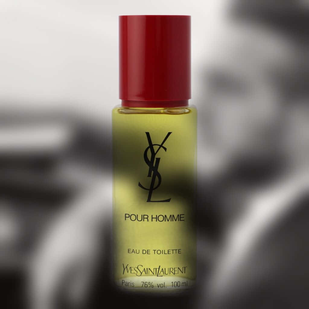以YSL為你的衣櫥增添風格 壁紙 — 一個時尚的 Yves Saint Laurent Pour Homme 香水瓶，帶有紅色瓶蓋和琥珀色液體，在模糊的黑白背景下清晰對焦。