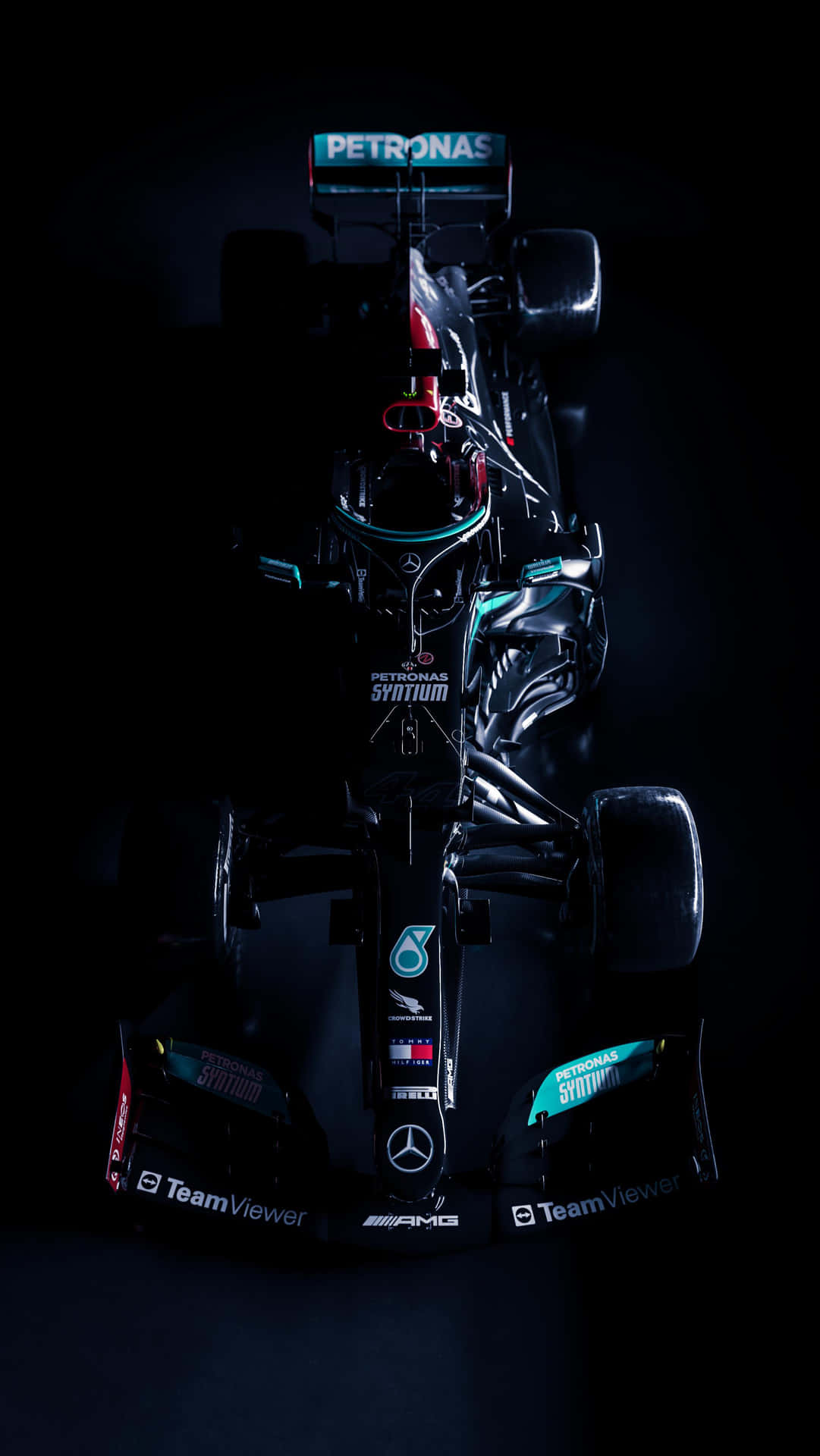 一輛帶有Petronas標誌的黑色和藍綠色一級方程式賽車，在黑暗的攝影棚中戲劇性地照亮。
