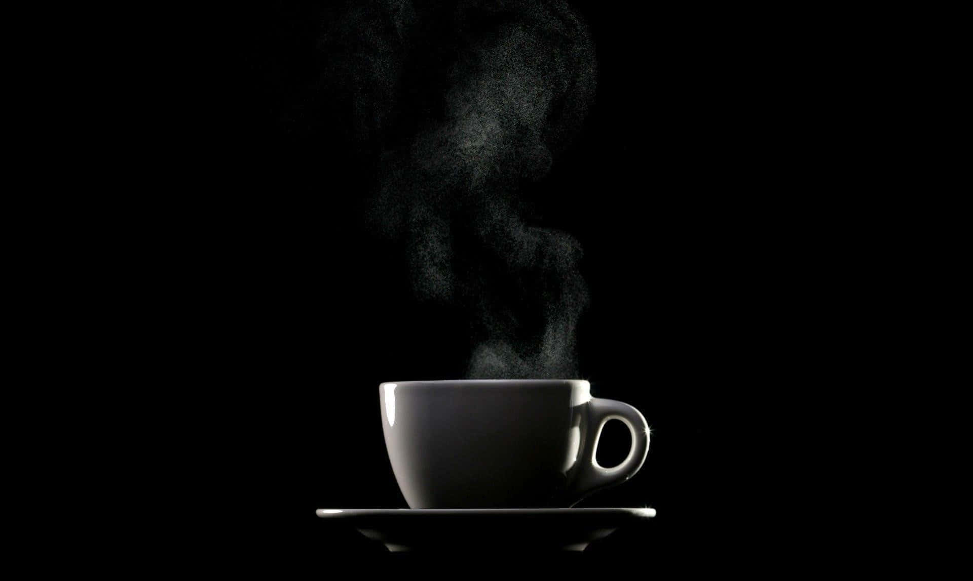 以一杯黑咖啡開啟美好一天 壁紙 — 一個冒著蒸氣的白咖啡杯放在碟子上，在純黑背景下柔和發光。