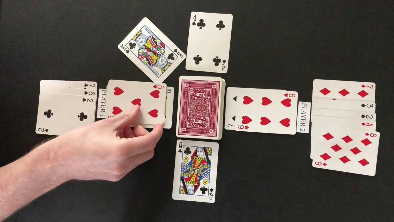 一隻手從黑色桌子上散落的啤牌中撿起一張啤牌。