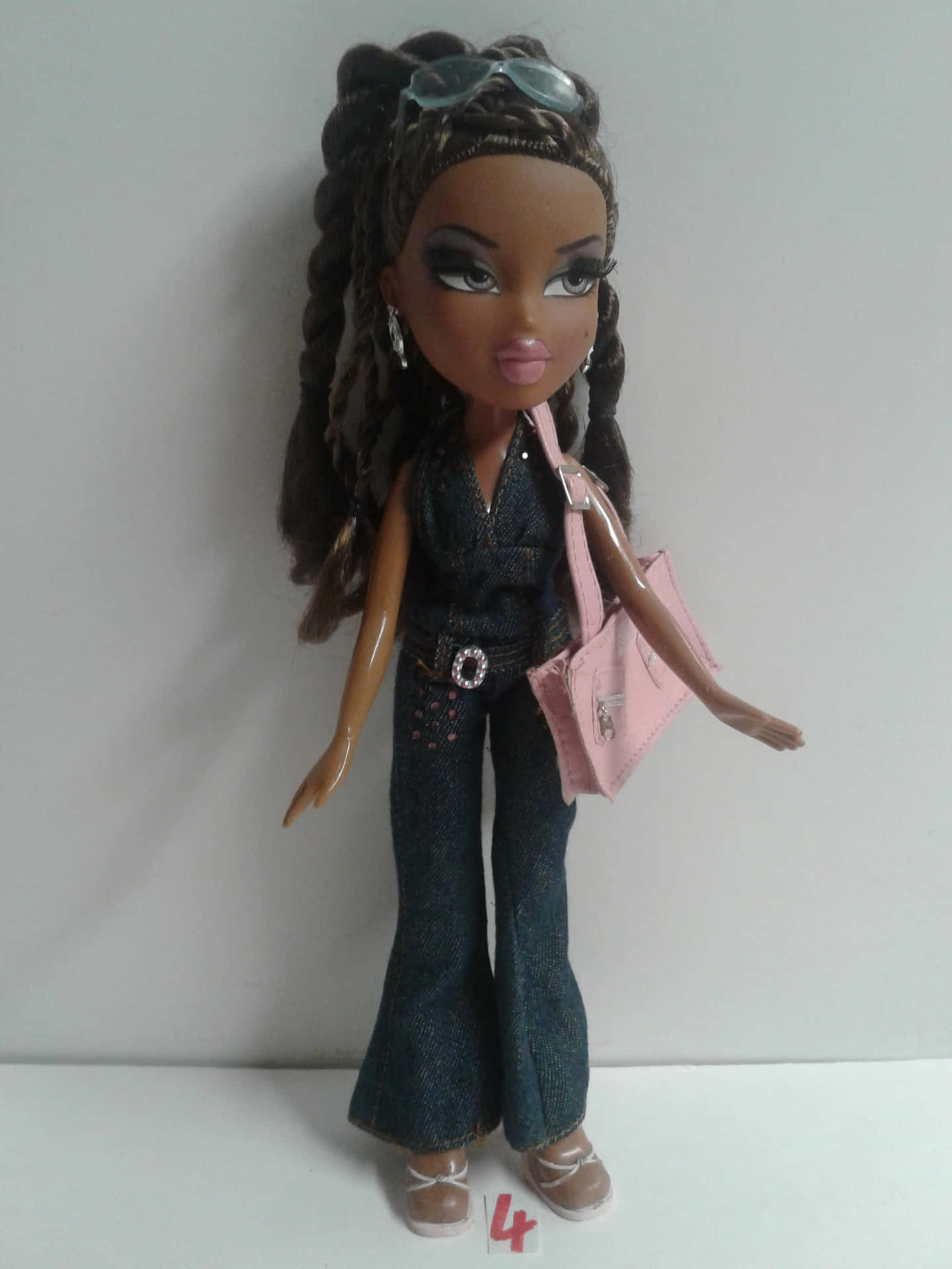身穿牛仔服、手持粉紅色手袋、頭上戴著太陽眼鏡的 Bratz 公仔。